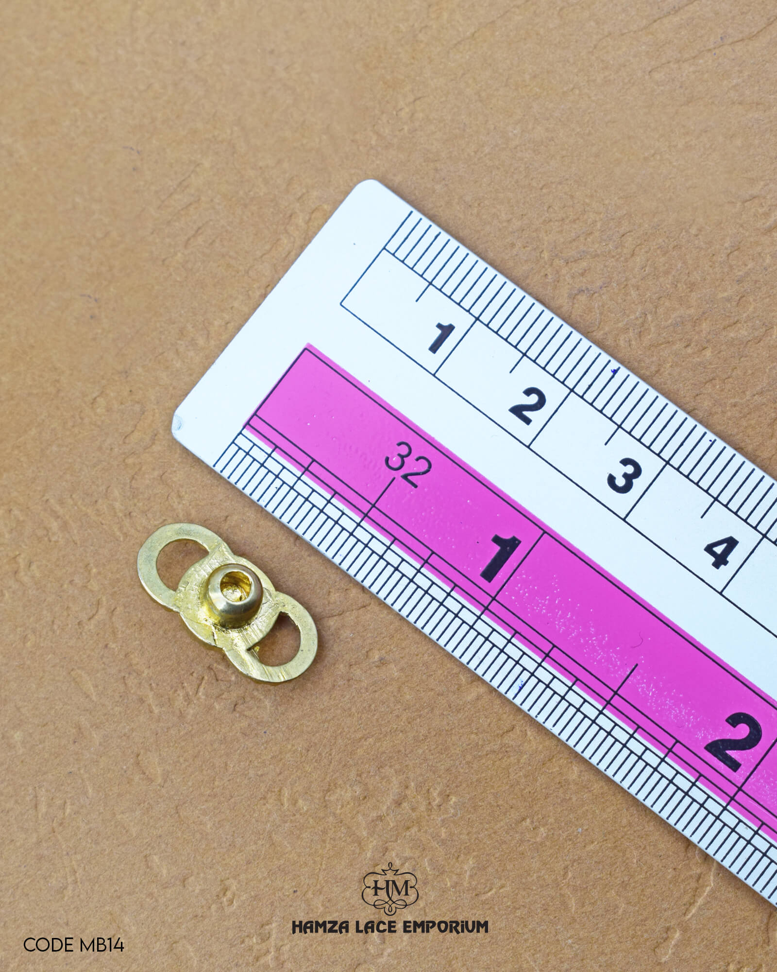 The dimensions of the 'Golden Metal Button With Stone MB14' are determined using a ruler.