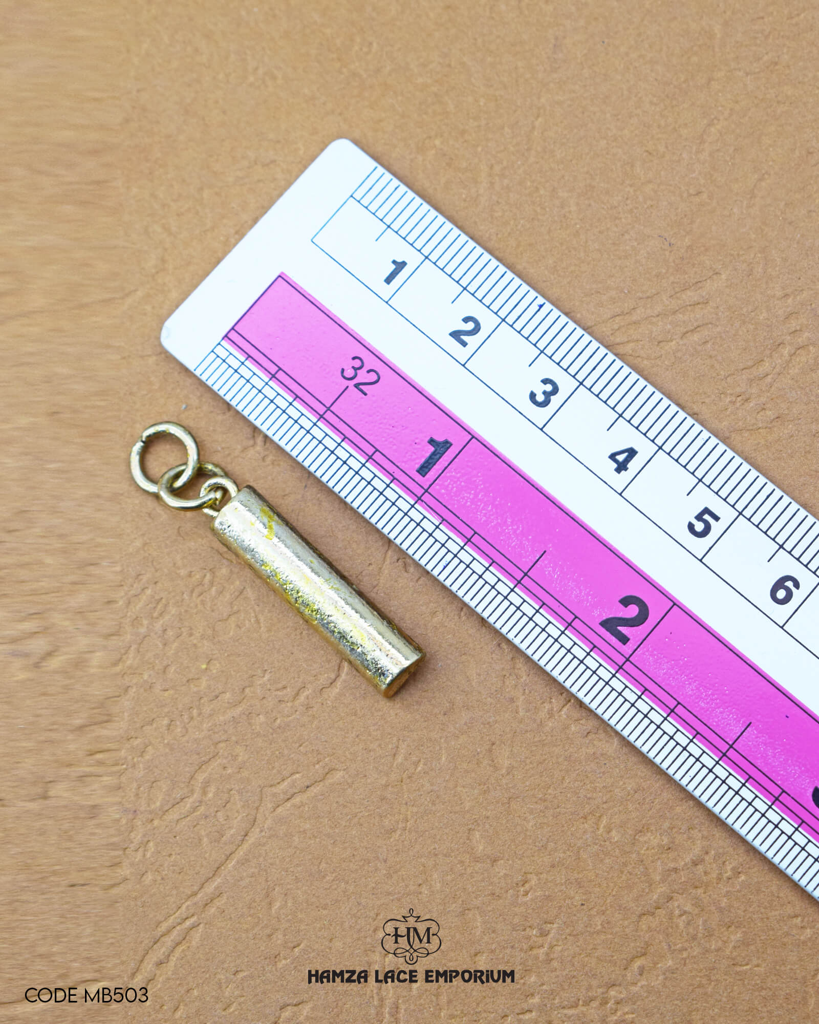 The dimensions of the 'Hanging Metal Button MB503' are determined using a ruler.