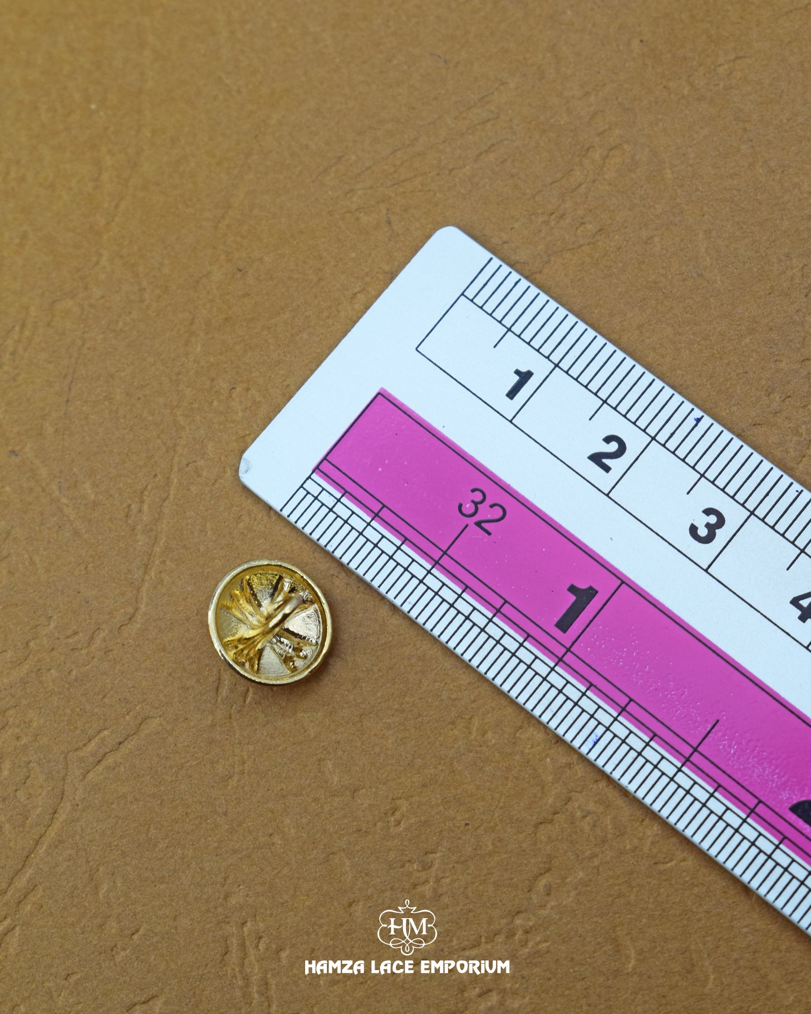 The dimensions of the 'Flower Design Golden Metal Button MB508' are determined using a ruler.