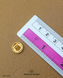 The dimensions of the 'Golden Metal Button MB76' are determined using a ruler.