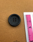 The size of the Beautifully designed 'Four Hole Black Plastic Button PB007' is measured by using a ruler