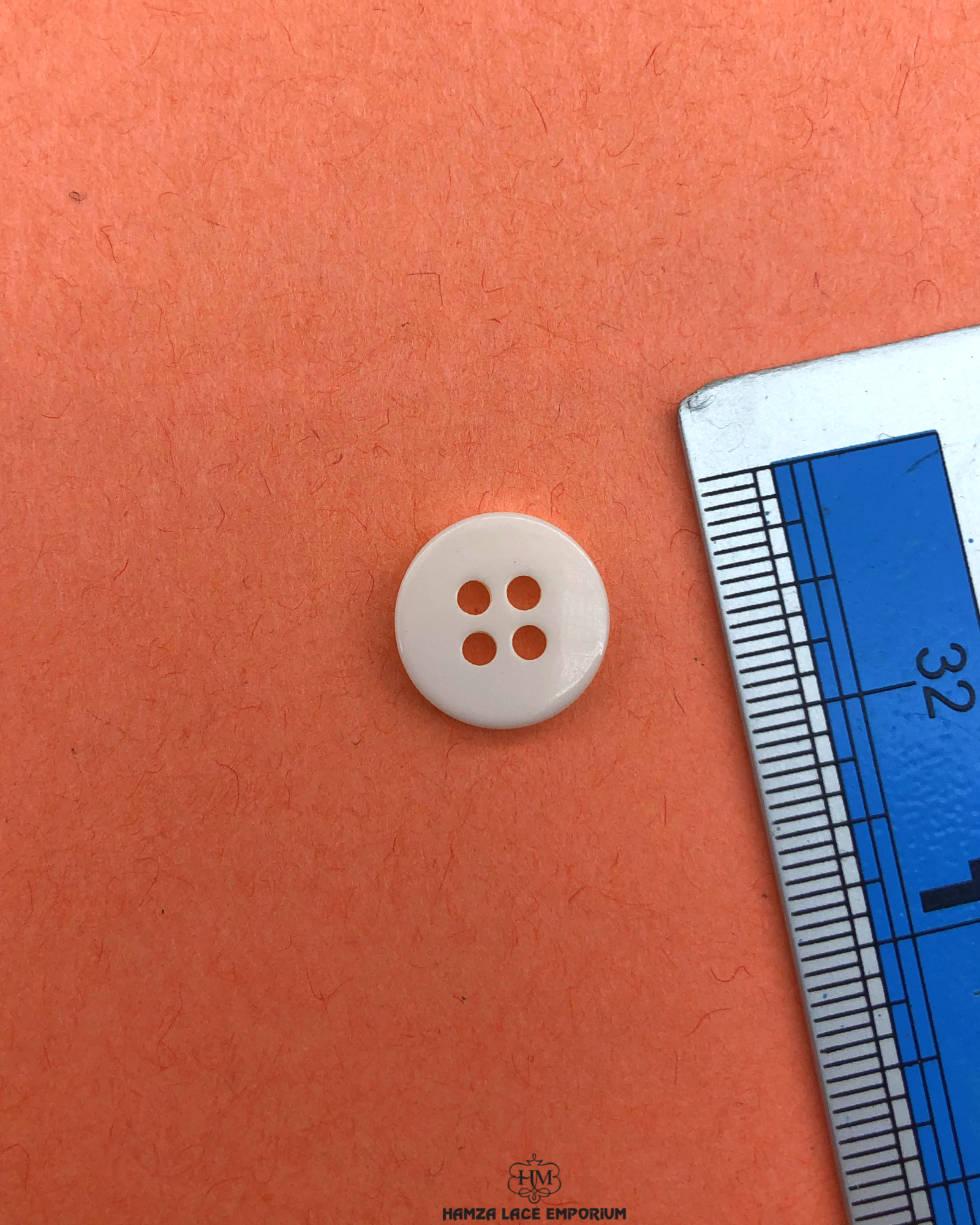 The size of the Beautifully designed 'Four Hole Plastic Button PB010' is measured by using a ruler